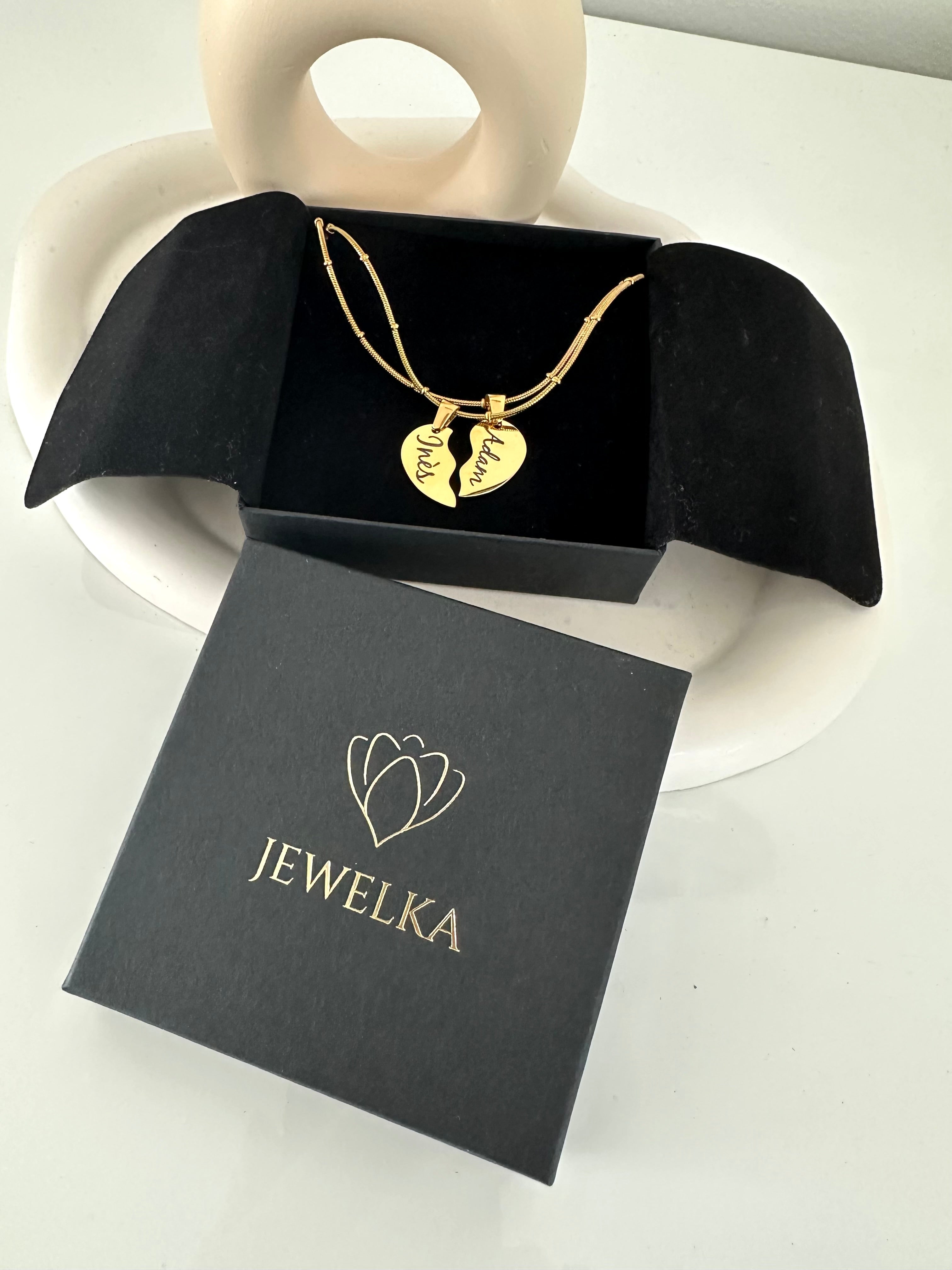 Double collier en acier doré avec deux moitiés de cœur dans un joli écrin. Bijou élégant et personnalisable, parfait comme cadeau symbolique pour un être cher.
